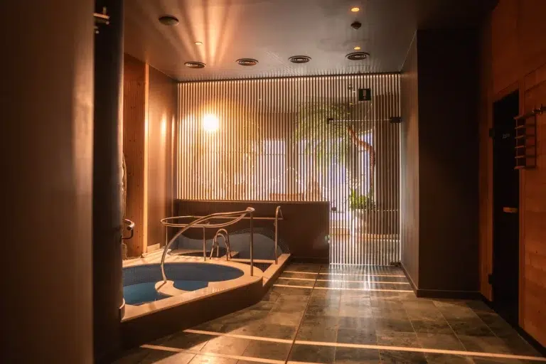 Modernes Indoor-Spa mit kleinem Pool, Metallgeländer und warmer Raumbeleuchtung.