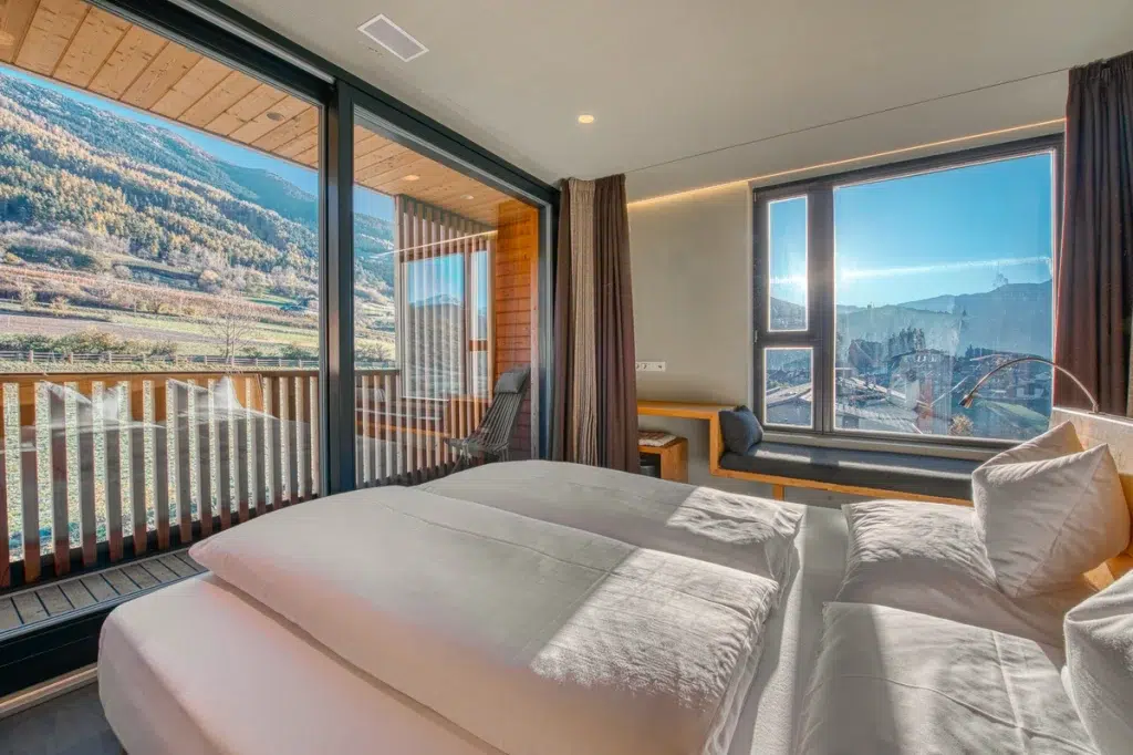 Modernes Hotelzimmer mit großen Fenstern, die eine schöne Aussicht auf die Berge bieten, und Balkon.