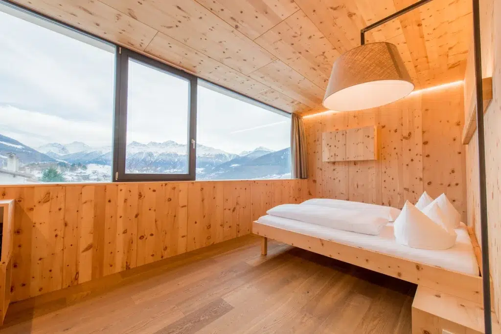 Minimalistisches Schlafzimmer aus Holz mit großen Fenstern und Bergblick.