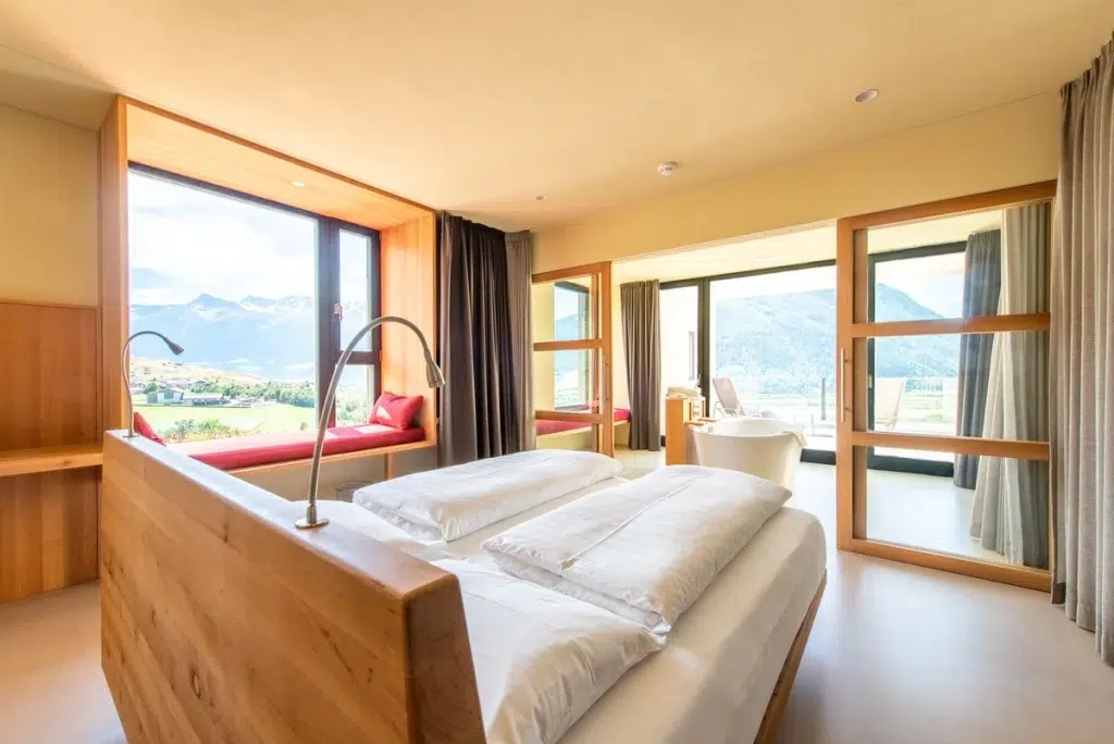 Modernes Hotelzimmer mit großen Fenstern, Bergblick und einem gemütlichen Fensterplatz.