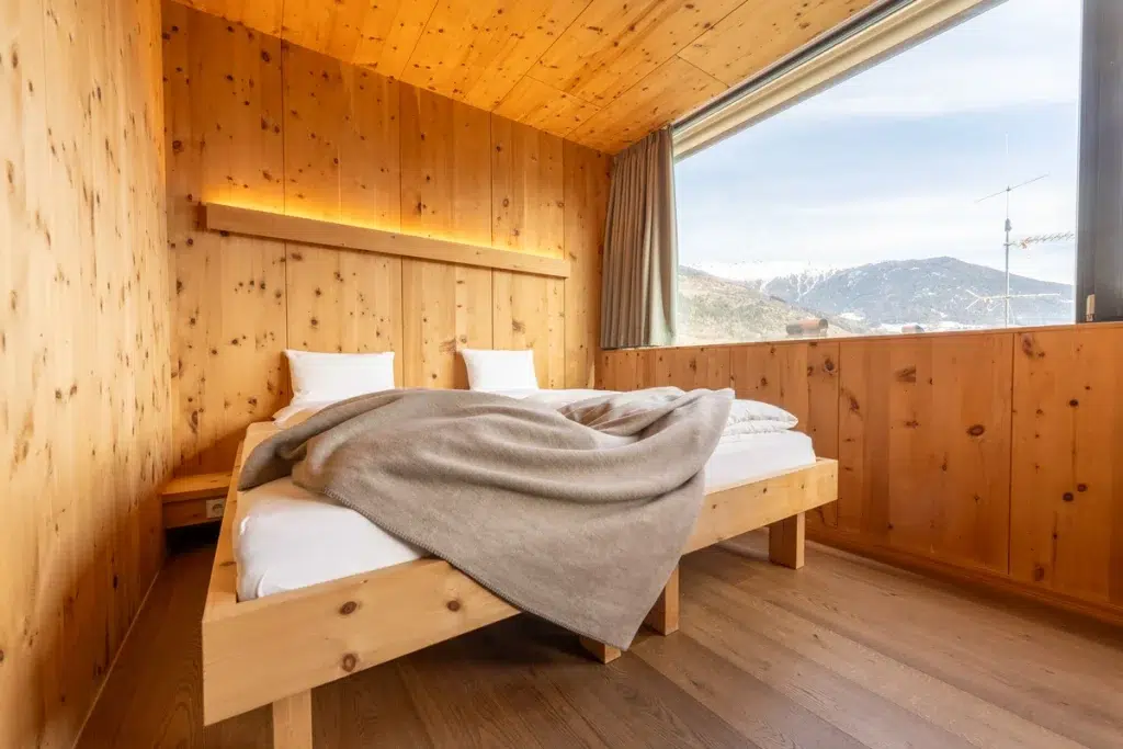 Gemütliches Holzschlafzimmer mit zwei Einzelbetten, großem Fenster und Bergblick.