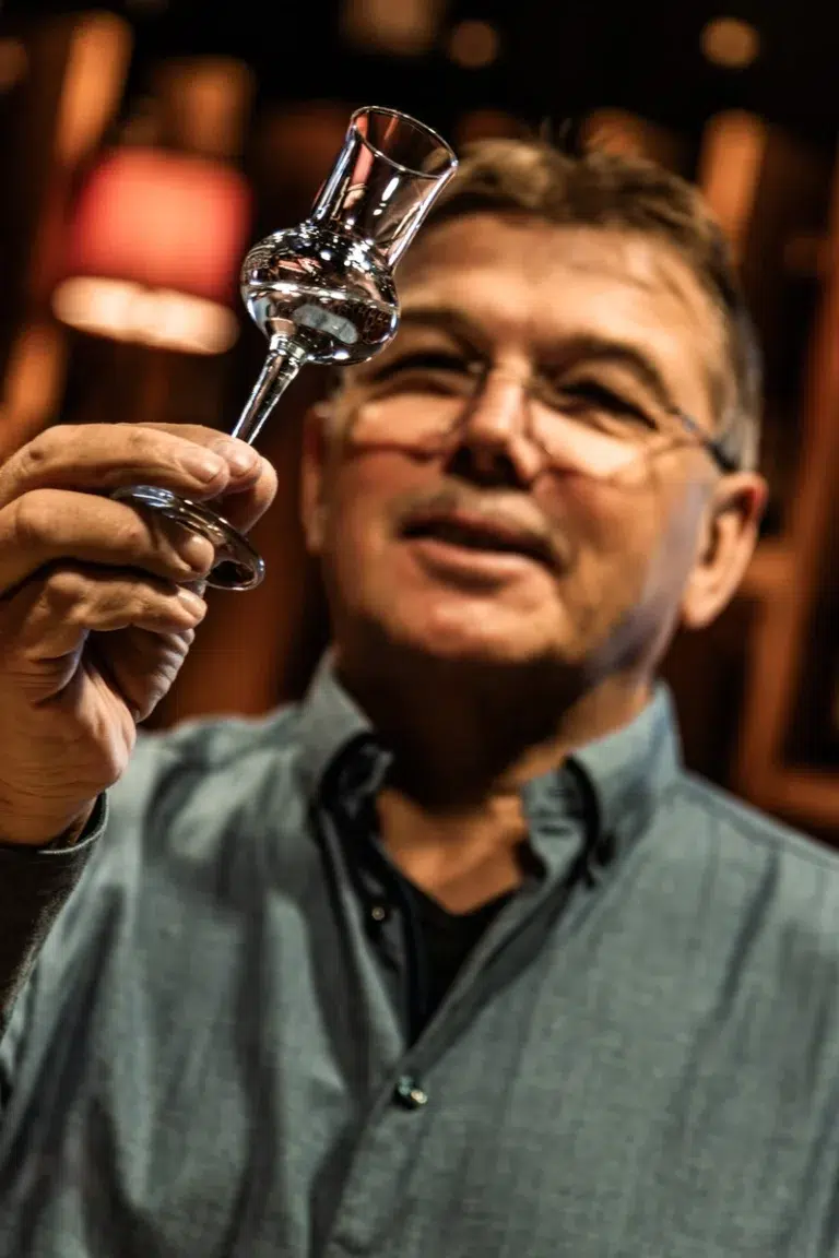 Ein Mann hält ein kleines Glas in der Hand und prüft den Inhalt genau.