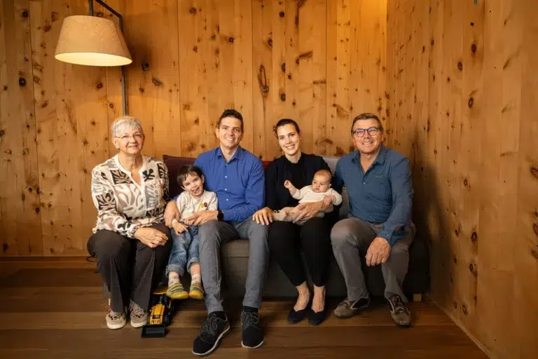 Eine sechsköpfige Familie sitzt auf einem Sofa in einem Biothotel geschichte und lächelt in die Kamera.